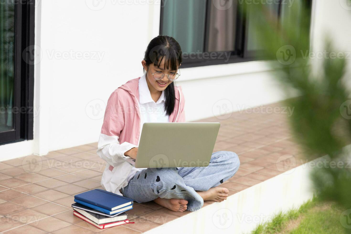 Student teen girl with glasses online learning with laptop computer photo