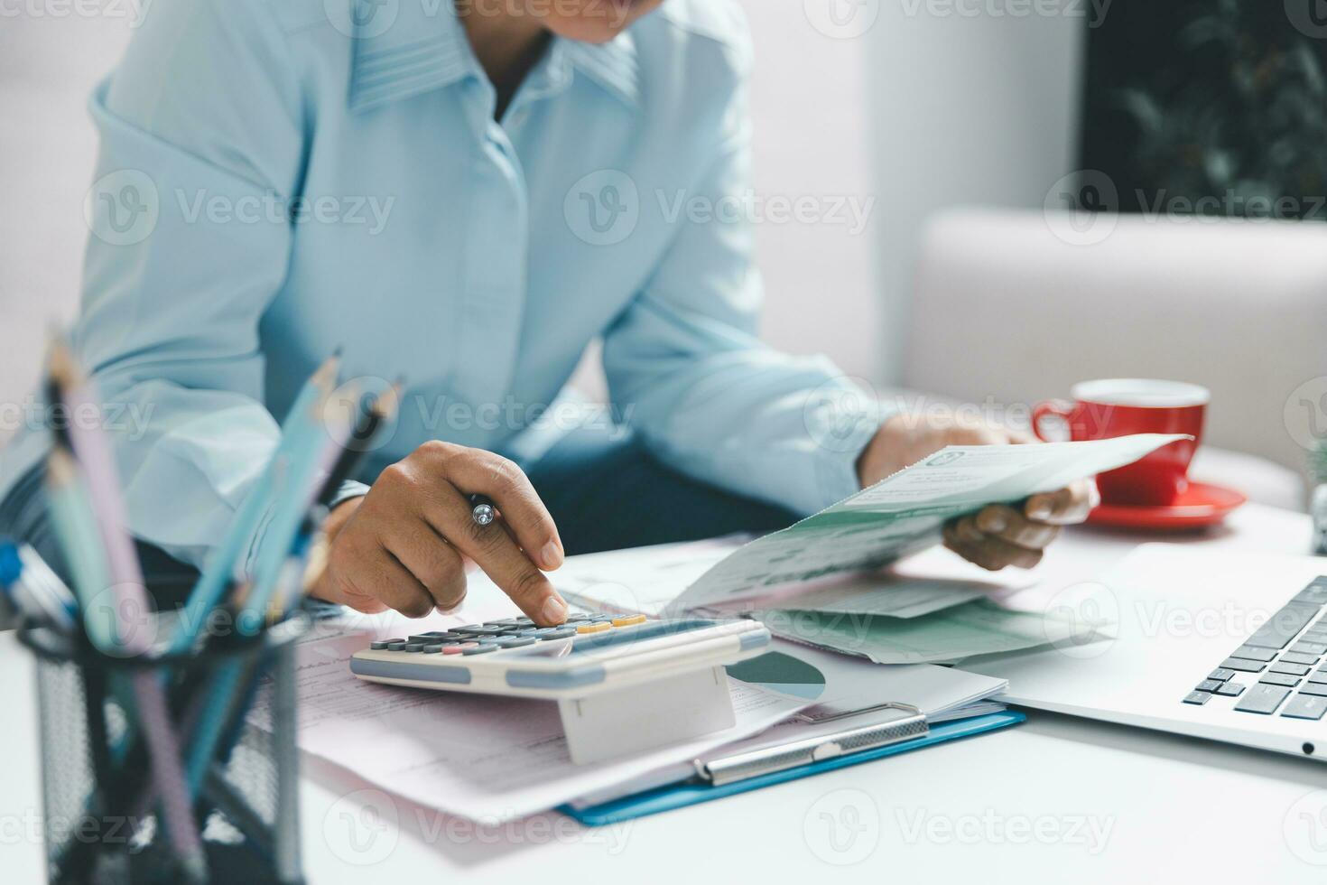 Close up Asian woman with calculator at laptop computer, analyzing benefit, job high result. Female work with financial papers at home count on calculator before paying taxes. photo