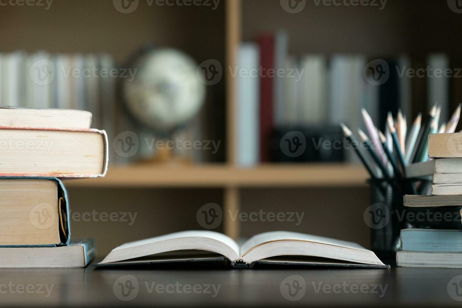 Education learning concept. Book in library with old open textbook, stack piles of literature text archive on reading desk, aisle of bookshelves in school study class room background for academic photo