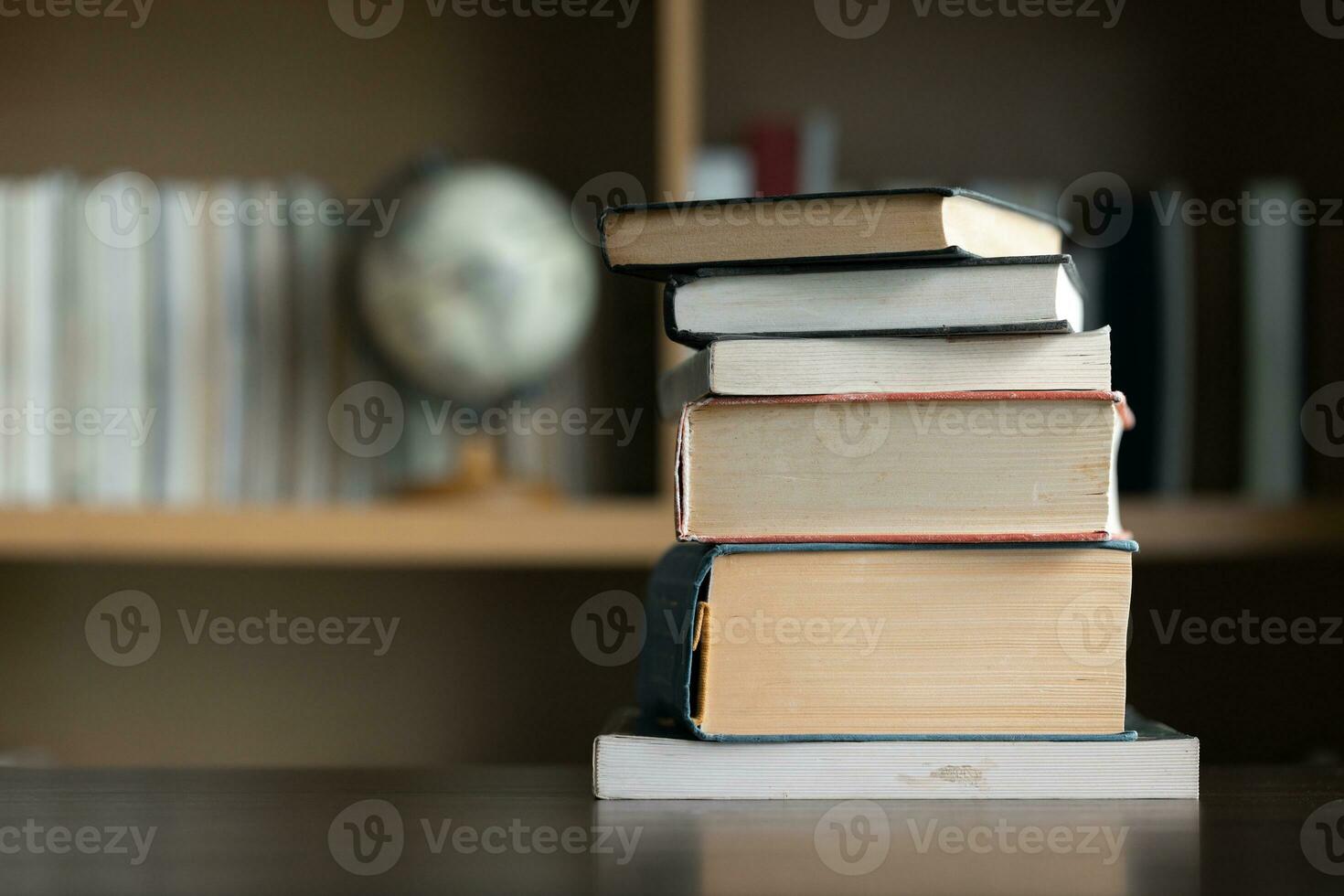 Education learning concept. Book in library with old open textbook, stack piles of literature text archive on reading desk, aisle of bookshelves in school study class room background for academic photo