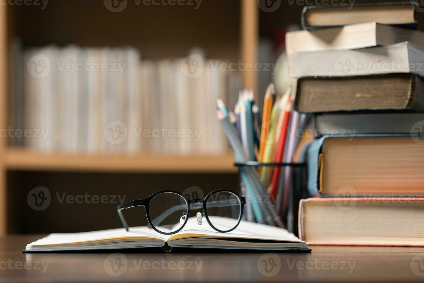 Education learning concept. Book in library with old open textbook, stack piles of literature text archive on reading desk, aisle of bookshelves in school study class room background for academic photo