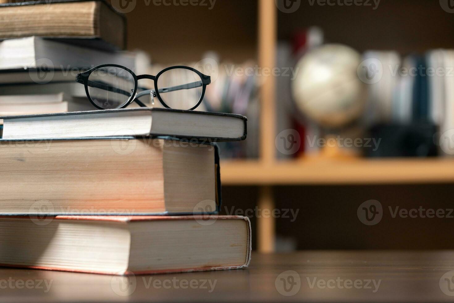 Education learning concept. Book in library with old open textbook, stack piles of literature text archive on reading desk, aisle of bookshelves in school study class room background for academic photo