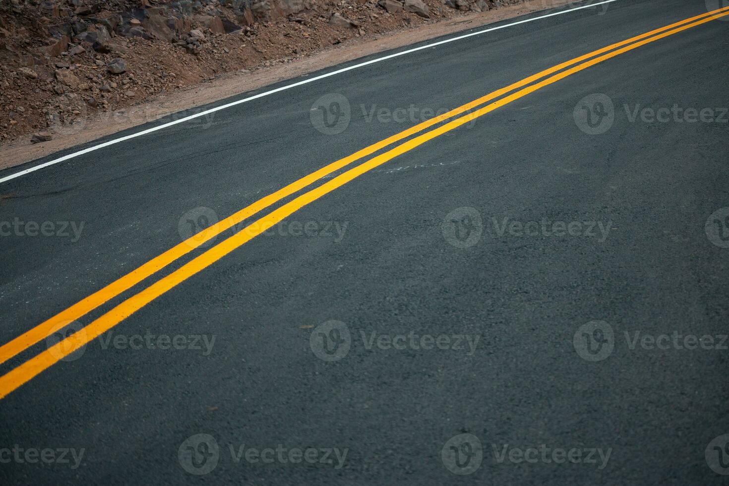 The asphalt road has yellow and white traffic lines crossing the mountains. photo