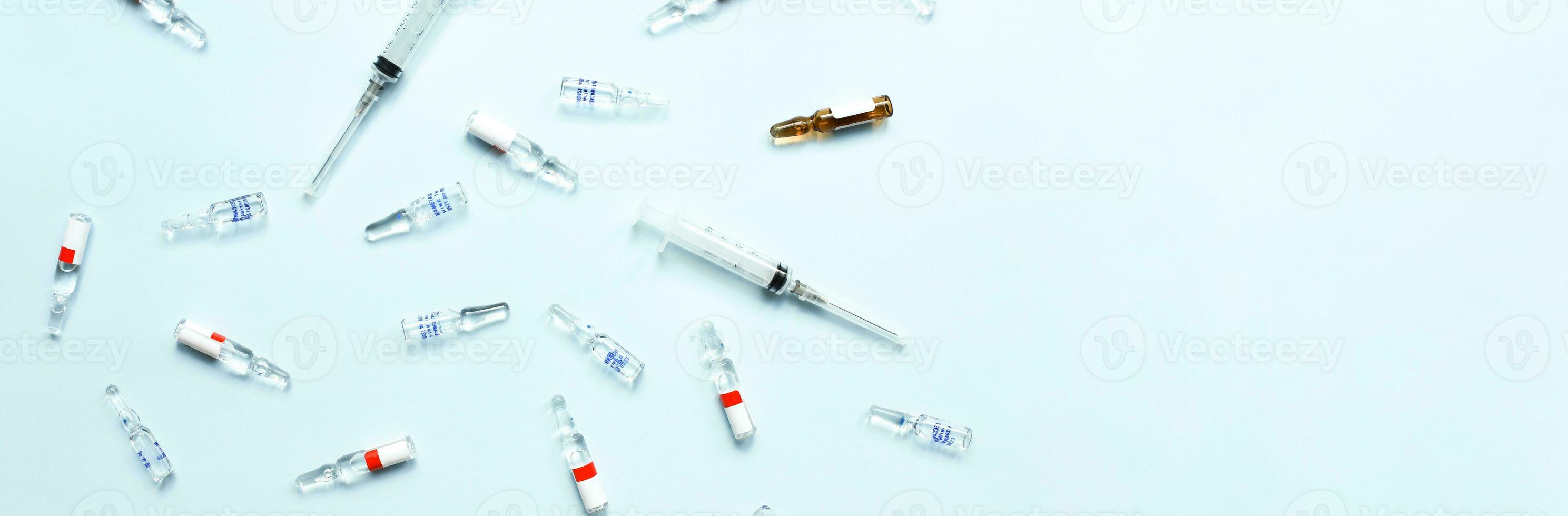 Banner Pattern of ampoules and syringes. Vaccination. Bird flu. Covid 19. Flat lay ampoules and medicines on a blue background photo