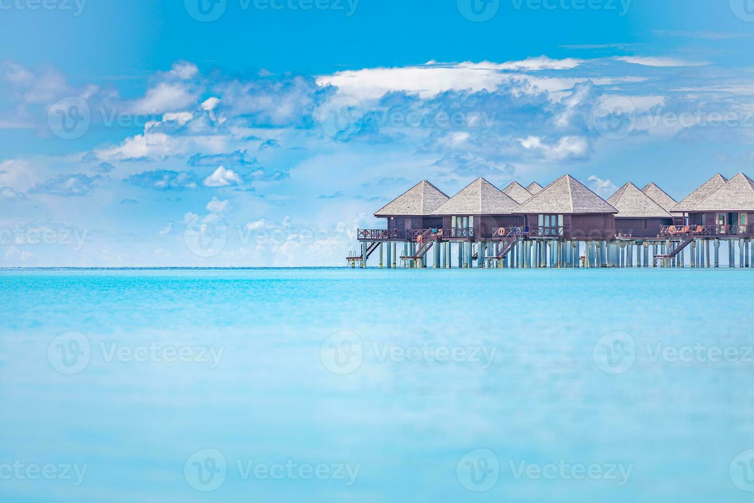 Luxury water villas in Maldives islands resort or hotel. View from the sea, peaceful tropical nature. Summer vacation and holiday banner. Beach landscape or seascape photo