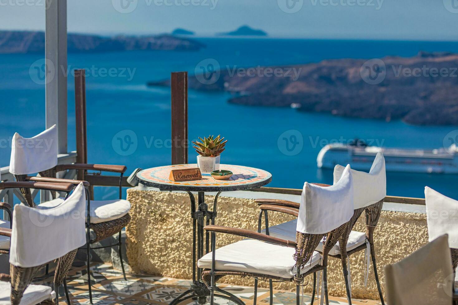 Restaurant with reserved tables in seafront of Aegean sea on Santorini Cyclades island with cruise ships in the background. Famous Europe travel tourism destination for summer vacation, vibes, mood photo