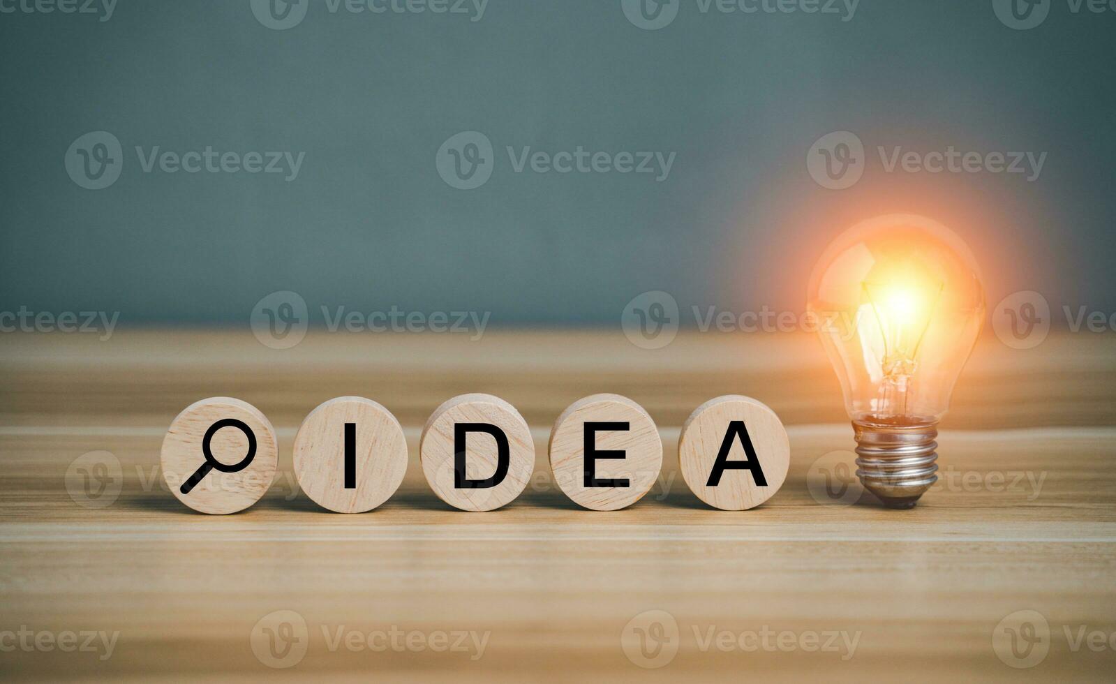Idea text and find symbol on circular wooden block with shining lightbulb. Creative success idea inspiration business concept innovation solution On the desk. photo