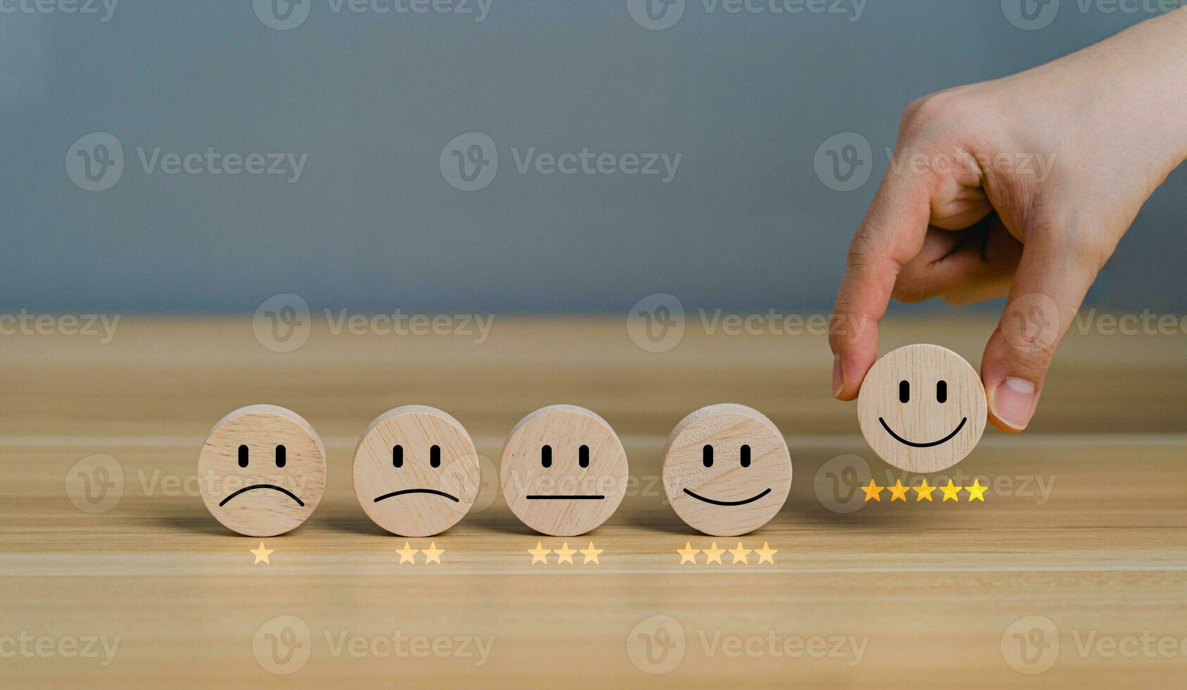 Hand picking happy smiley face icon on circular wooden block, 5 Star Satisfaction. Customer service experience and business satisfaction survey. Rating very impressed. Satisfaction survey concept. photo