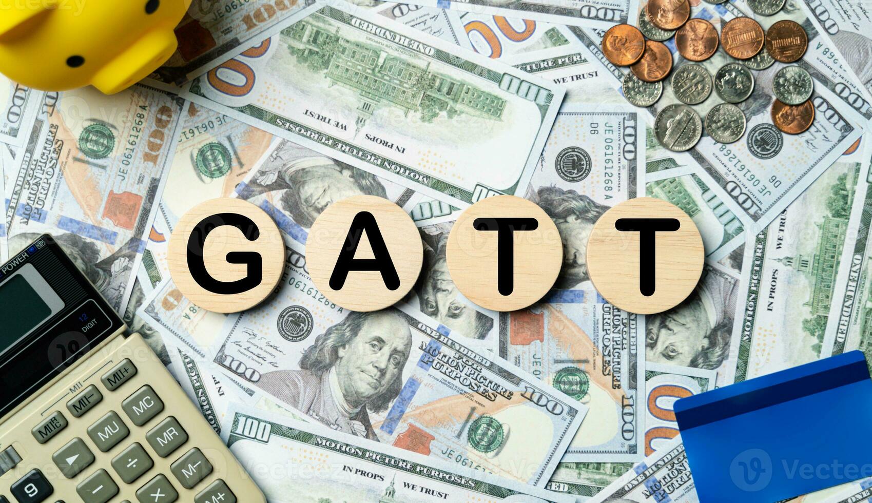 GATT text in wooden circle on Banknotes background, credit card, piggybank, calculator. General agreement on tariff and trade, Future, goals, opportunity, business strategy and financial concept. photo