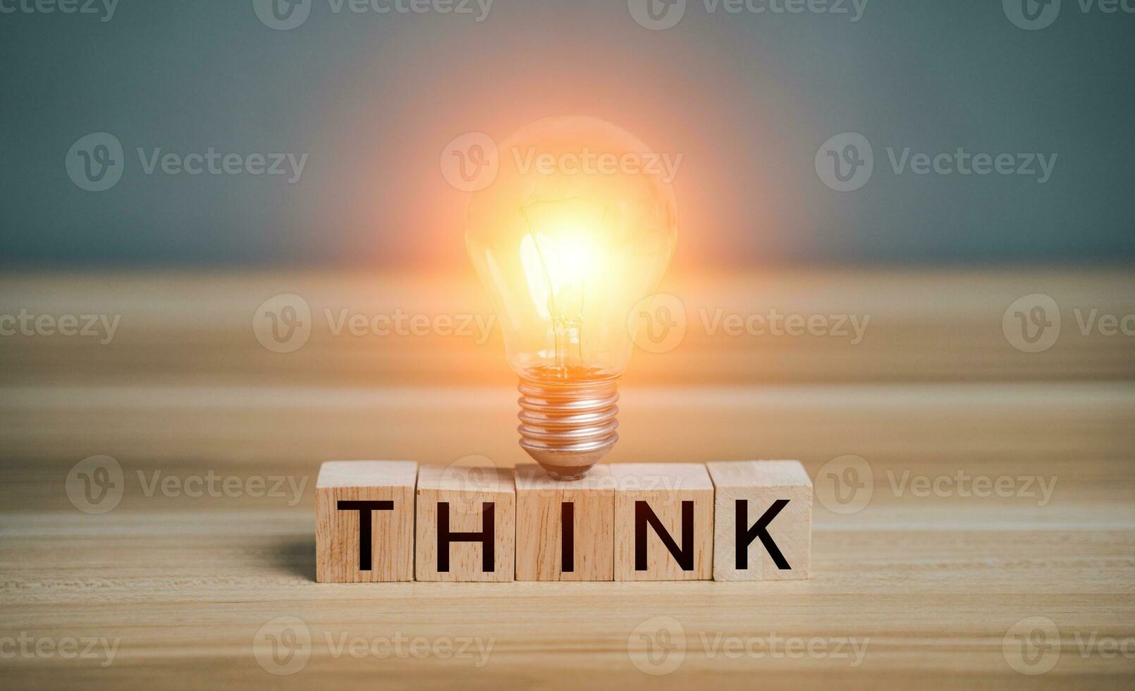 Think text on Woods block square with shining lightbulb. Creative success idea inspiration business concept innovation solution On the desk. photo