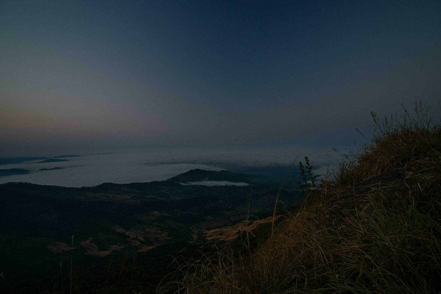 The stunning view from a tourist's standpoint as they go down a hill on a foggy trail with a hill and a background of a golden sky in Phu Langka Forest Park in Phayao, Thailand. photo