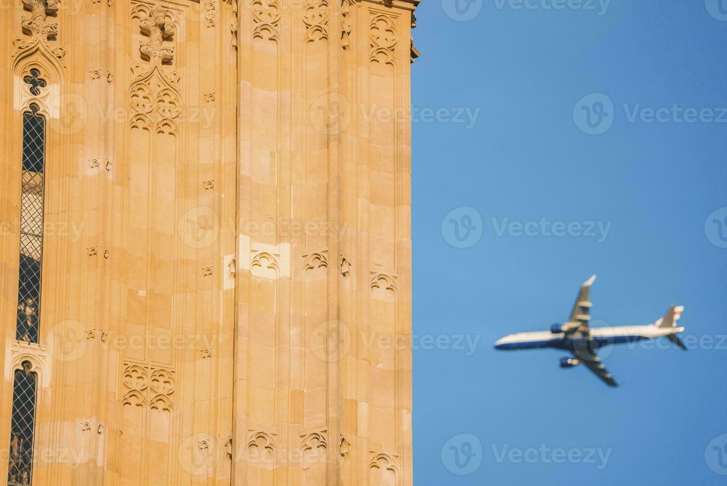 Airplane flying by Big Ben with clear blue sky in background photo
