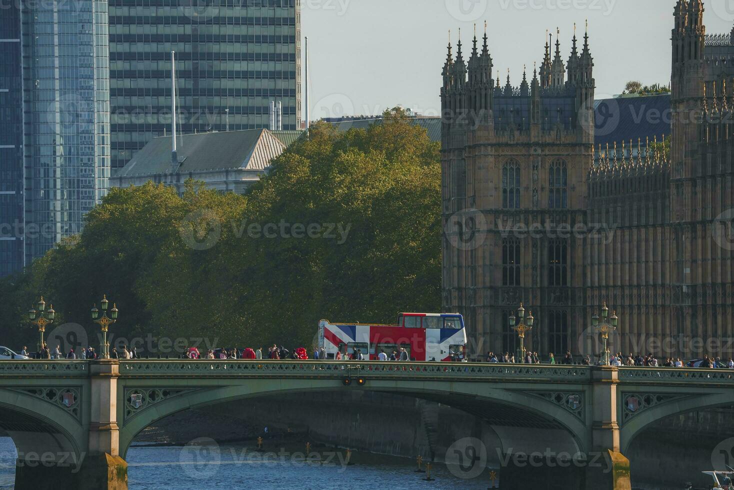 People exploring Westminster bridge over Thames river with palace in background photo