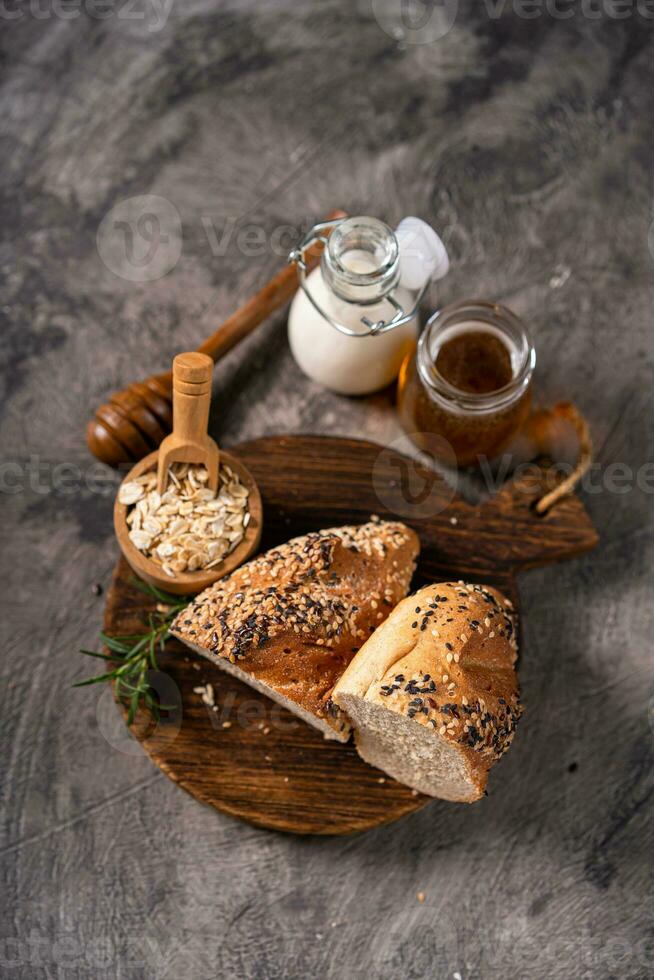 Artisan bread whole wheat baguette white milk and honey on rustic wooden board and abstract table. Sourdough bread photo