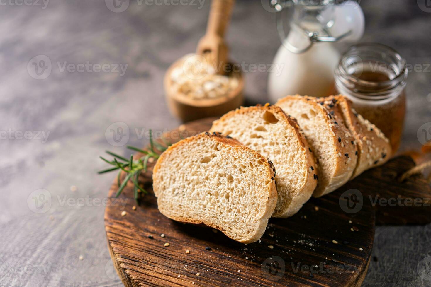Artisan bread whole wheat baguette white milk and honey on rustic wooden board and abstract table. Sourdough bread photo