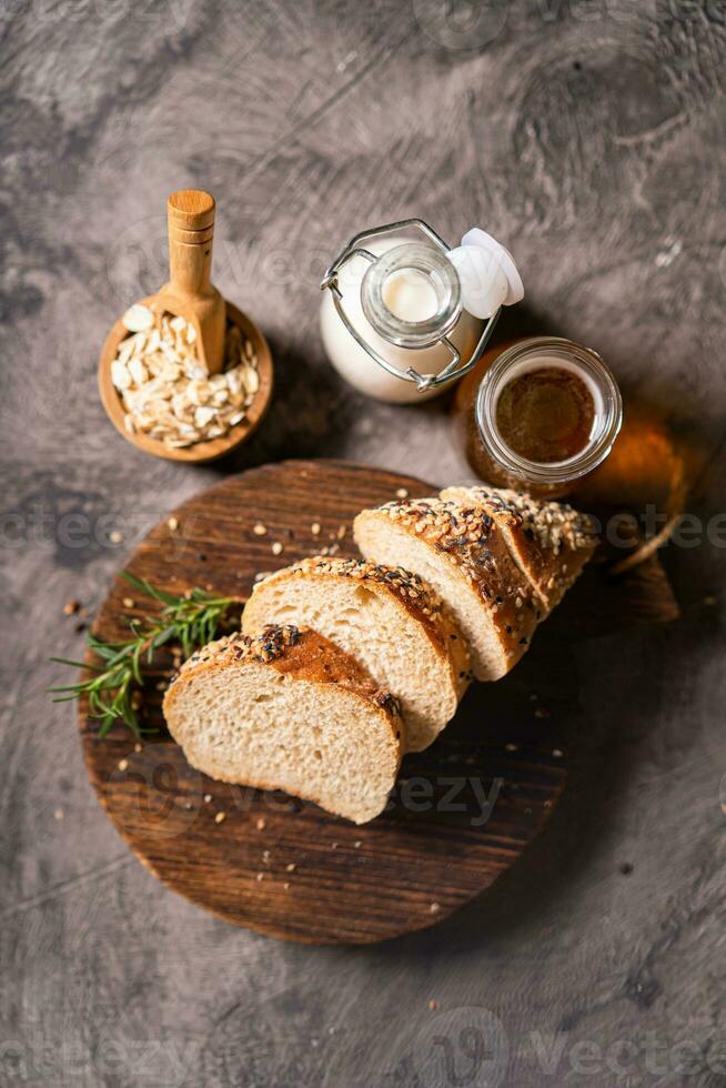Artisan bread whole wheat baguette white milk and honey on rustic wooden board and abstract table. Sourdough bread photo