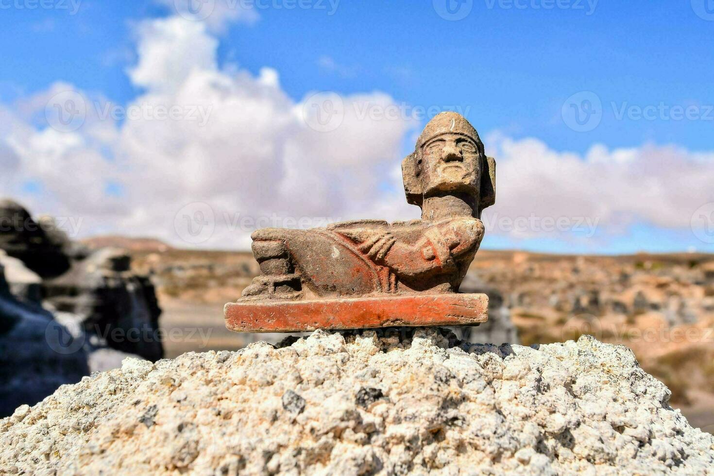 ancient statue of a man sitting on a rock photo