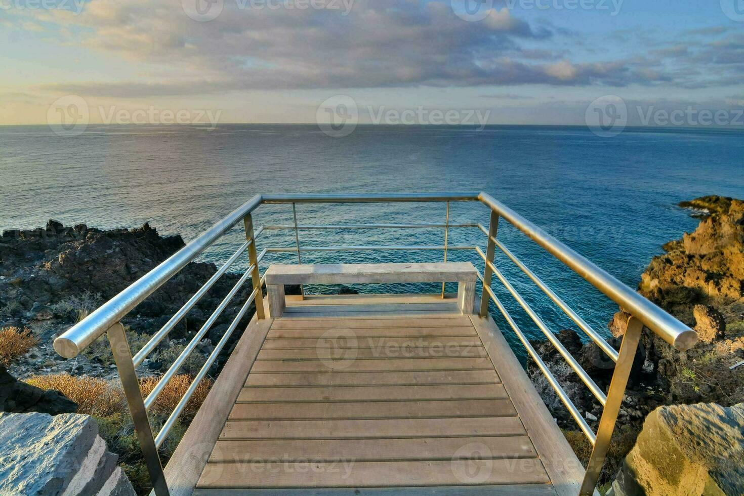 a walkway with a railing leading to the ocean photo