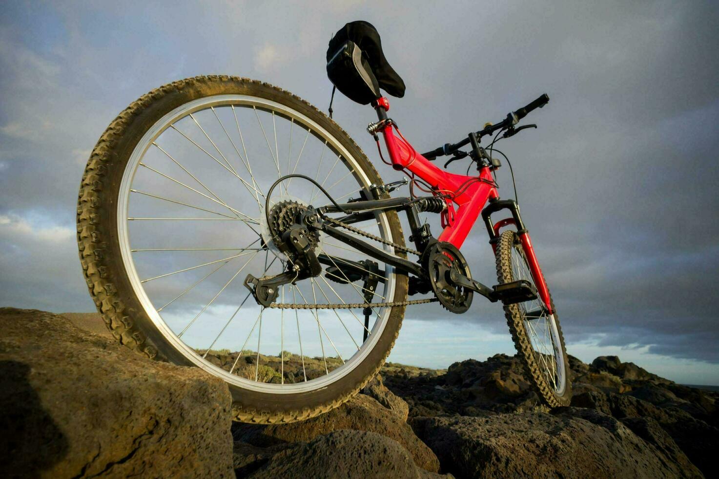 a red mountain bike sits on top of a rocky hill photo