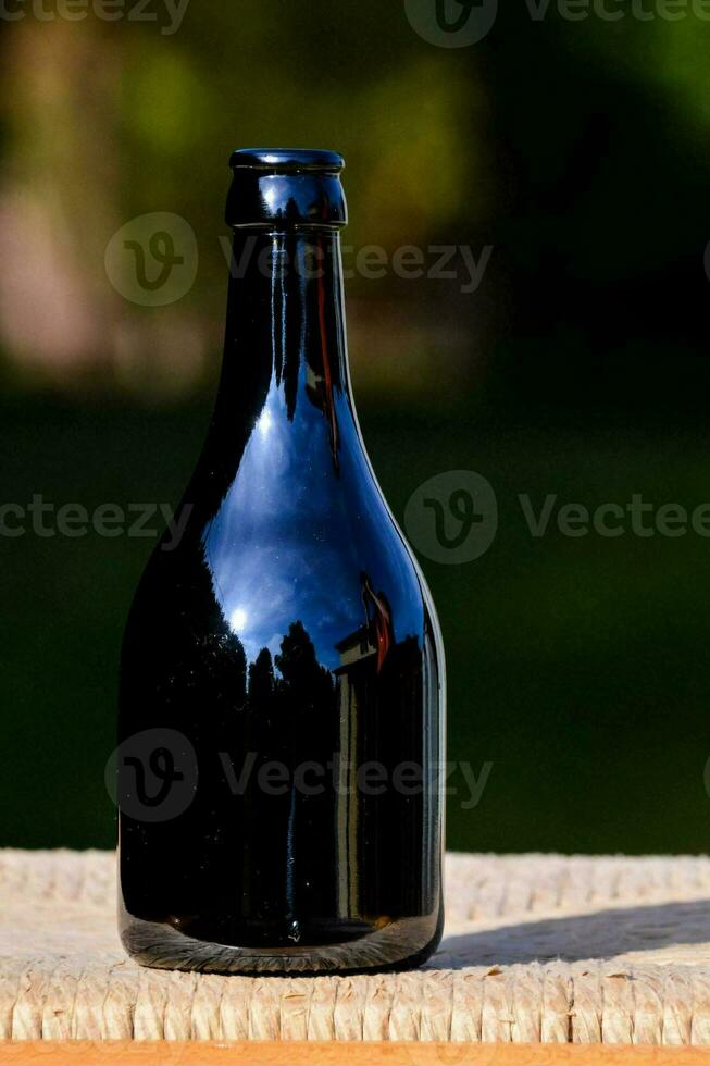 a black bottle sitting on top of a wooden table photo