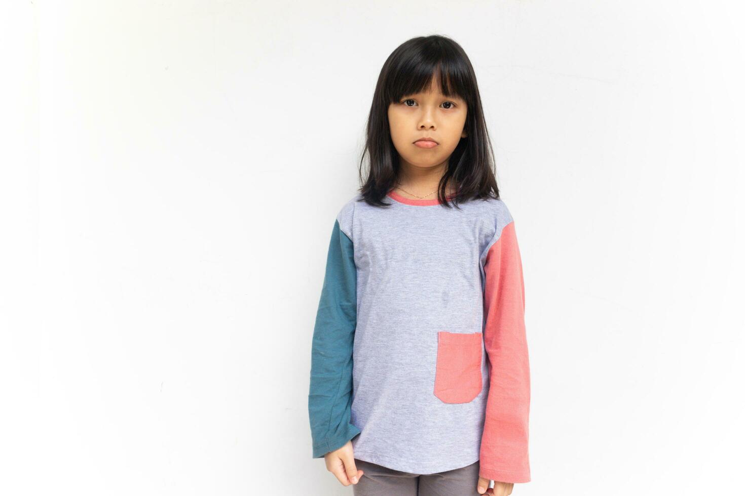 A sad girl sulking and frowning disappointed, standing upset and distressed against white background photo