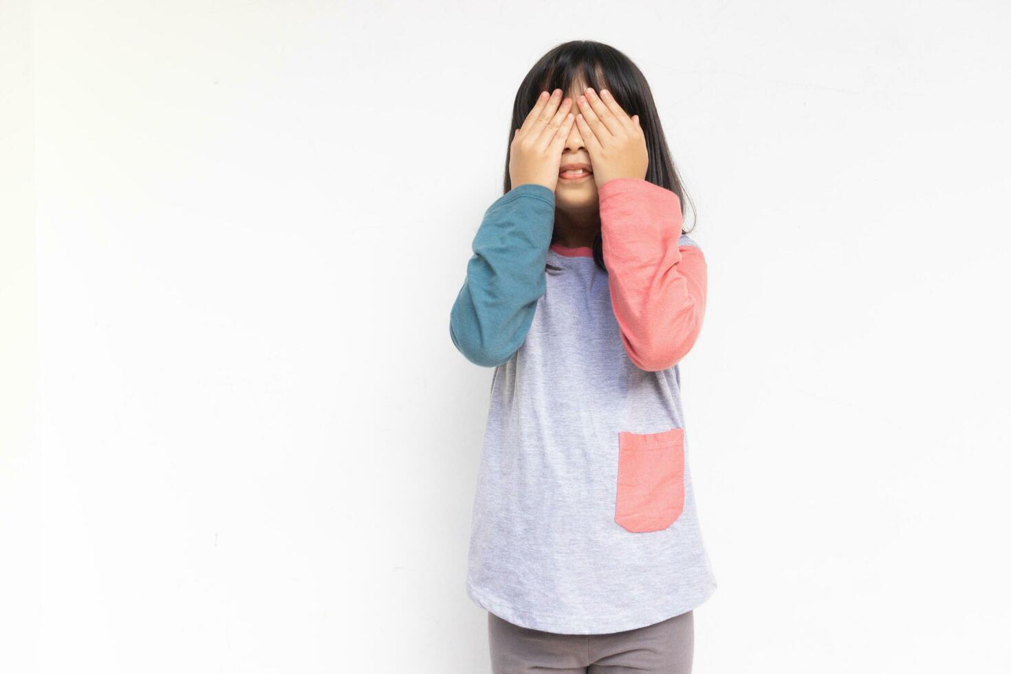 A cute smiling girl covering his eyes, playing hide and seek photo