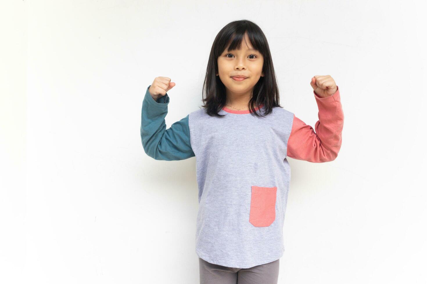 A cute confident girl looking at camera raised hands showing her bicep muscle photo