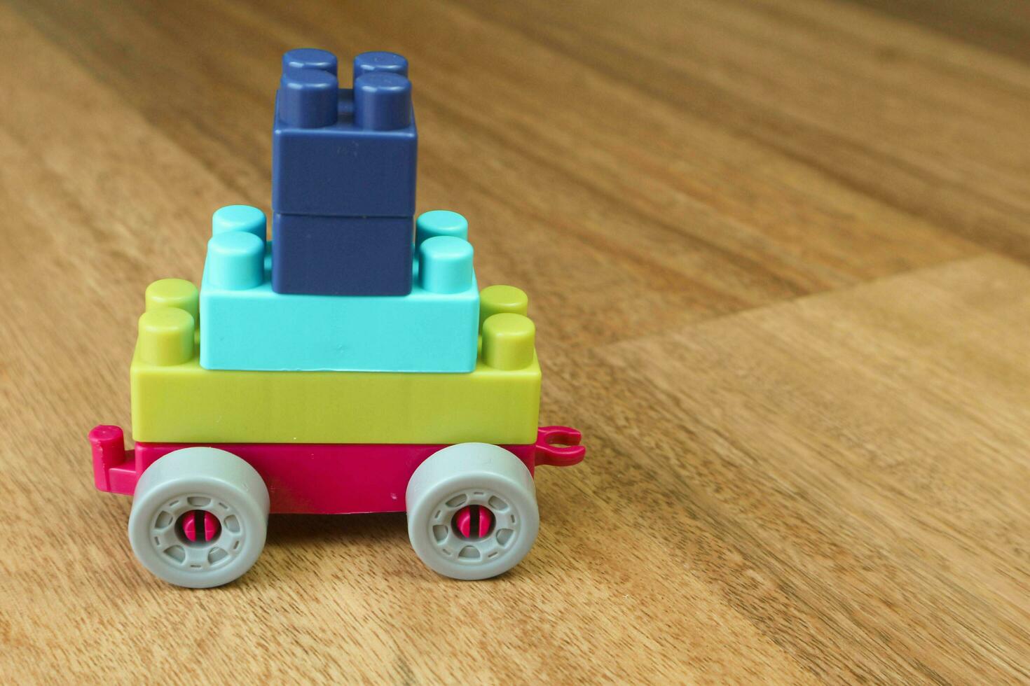 Plastic building blocks form vehicle on wooden background photo