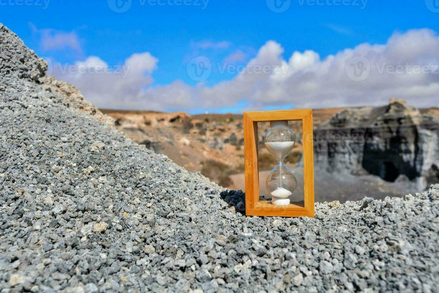 un reloj de arena en el suelo en un rocoso paisaje foto