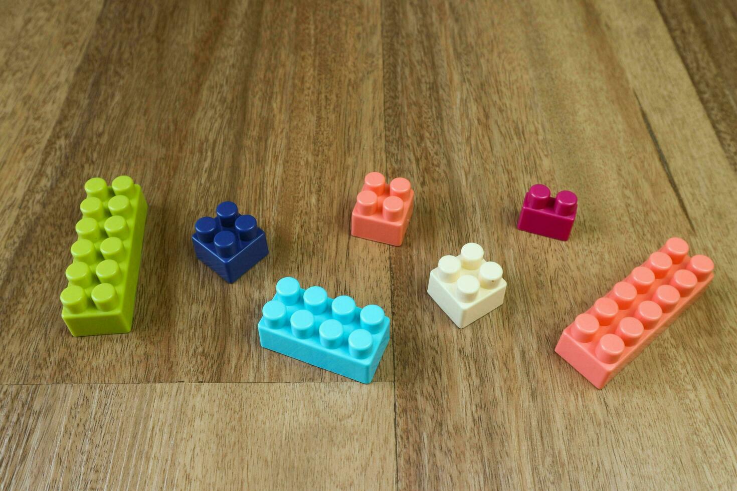 Pieces of plastic building blocks on wooden background photo