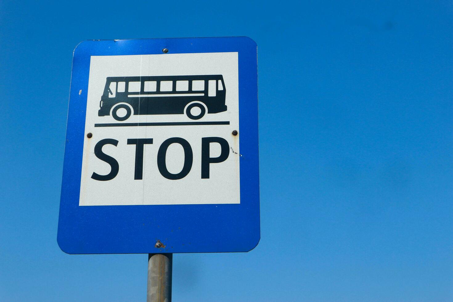 Bus stop sign on the bright sky photo