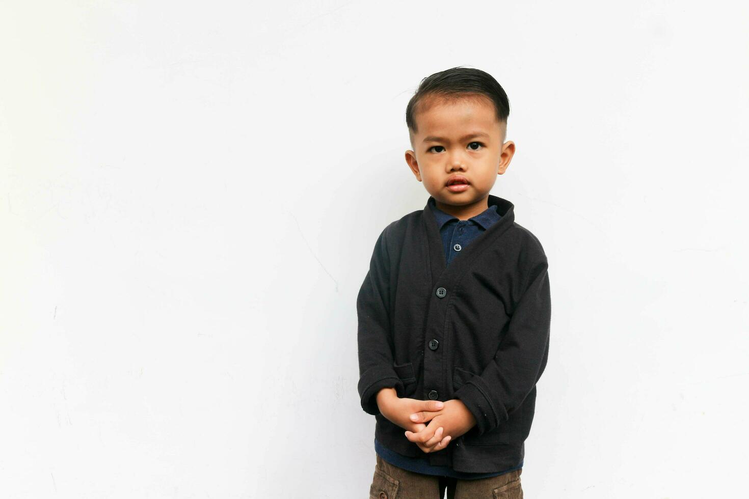 A toddler boy standing while looks at the camera with confidence, isolated on white background photo