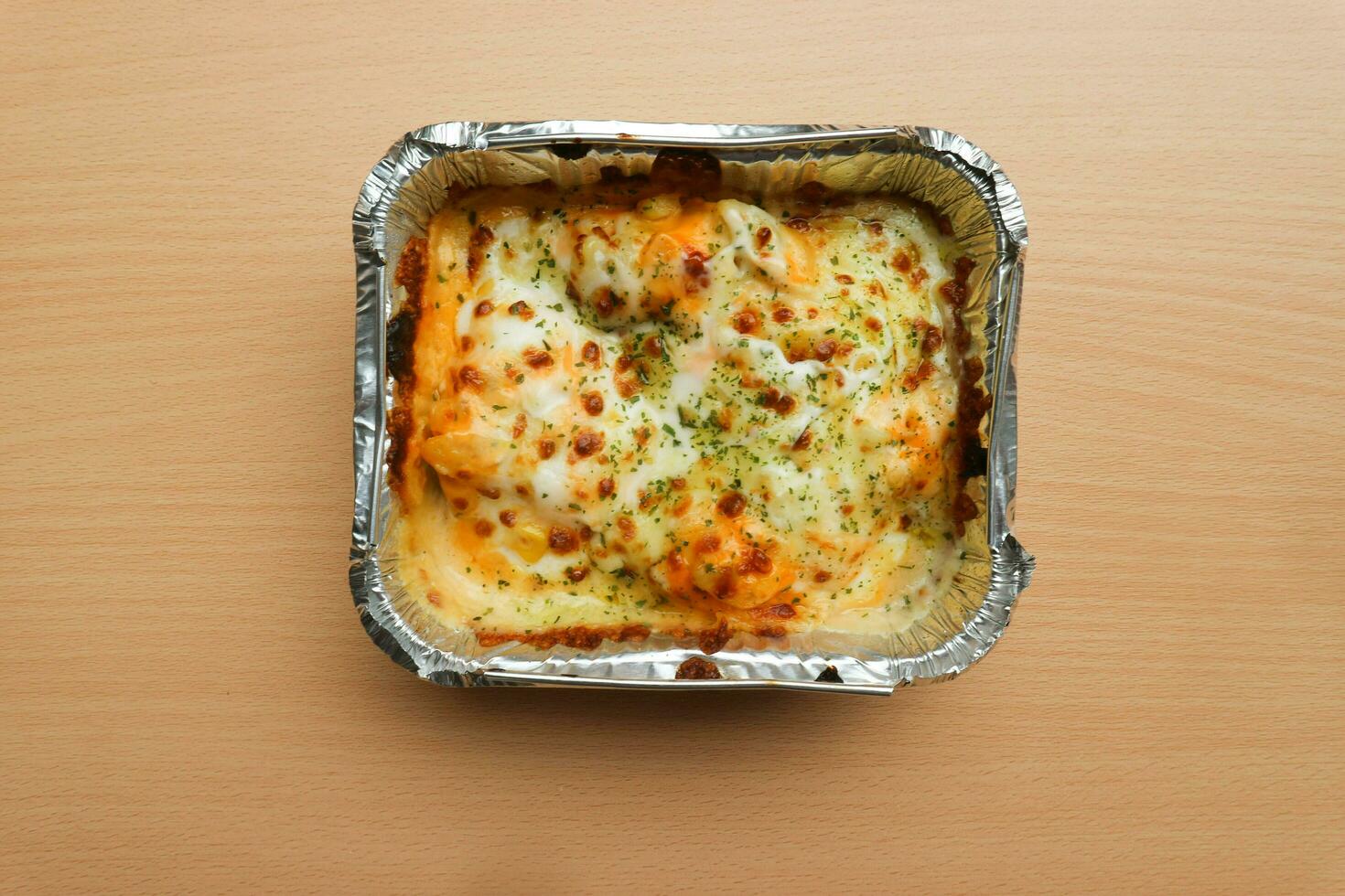 Pasta Makaroni Saus Keju or Pasta Mac and cheese in the aluminium foil bowl on the wooden background photo