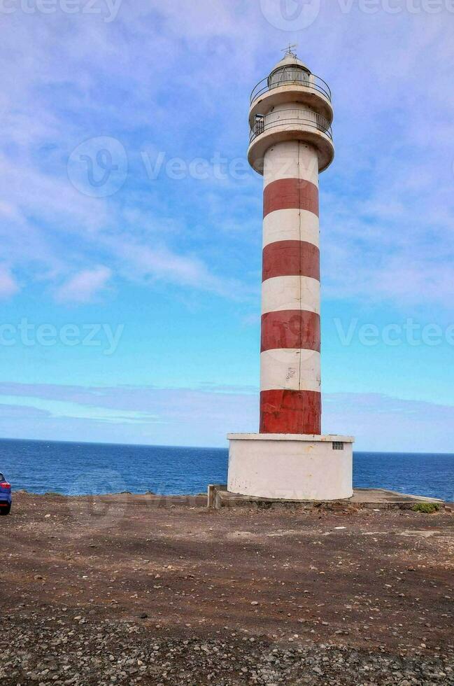 a red and white striped lighthouse on the coast photo