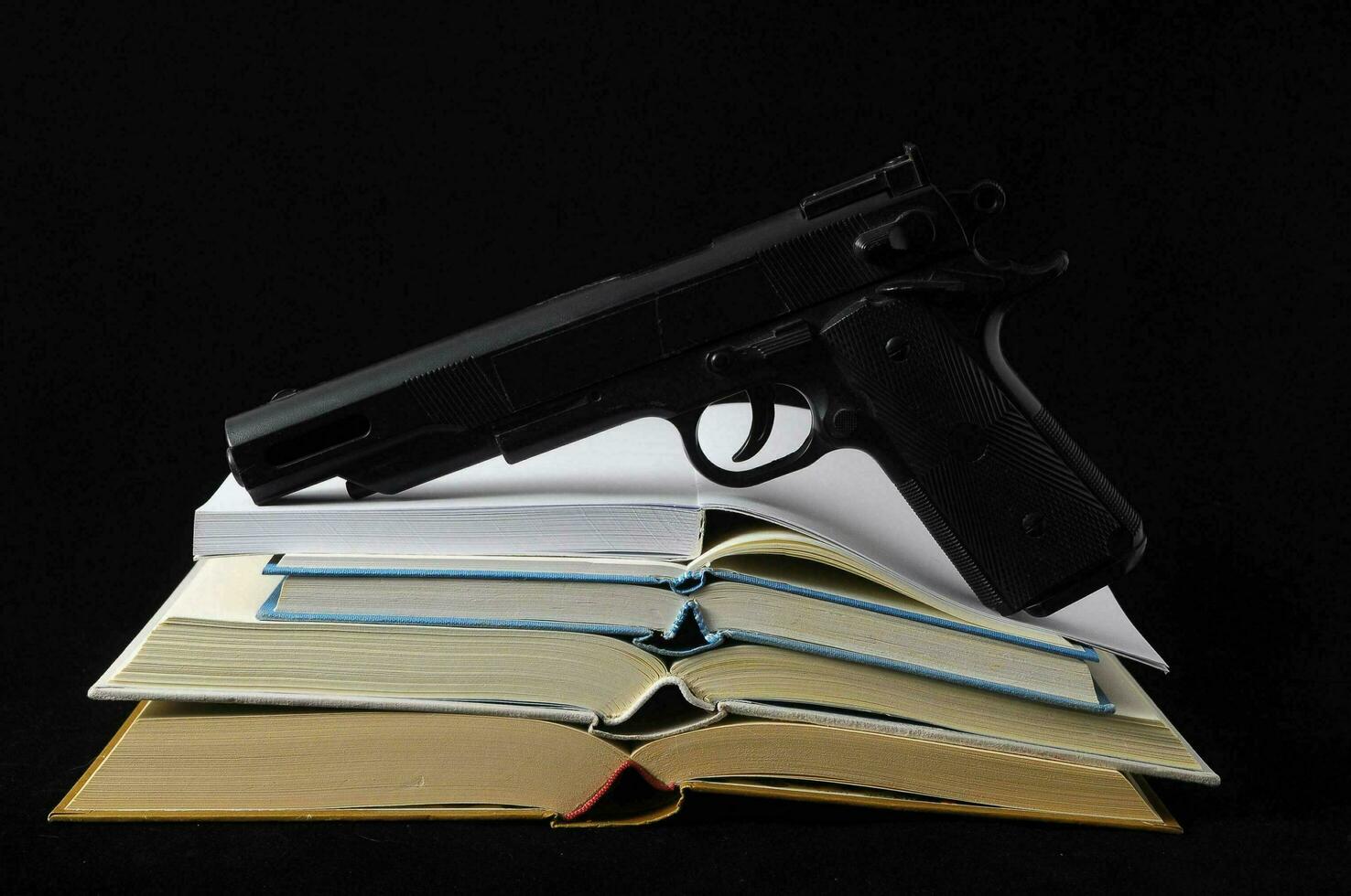 a gun and books on a black background photo