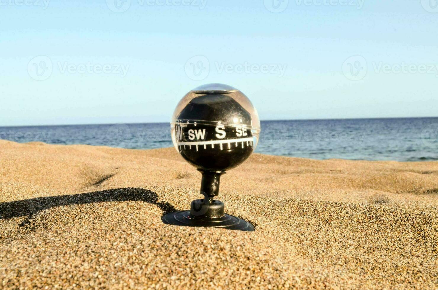 a compass on the beach with the ocean in the background photo