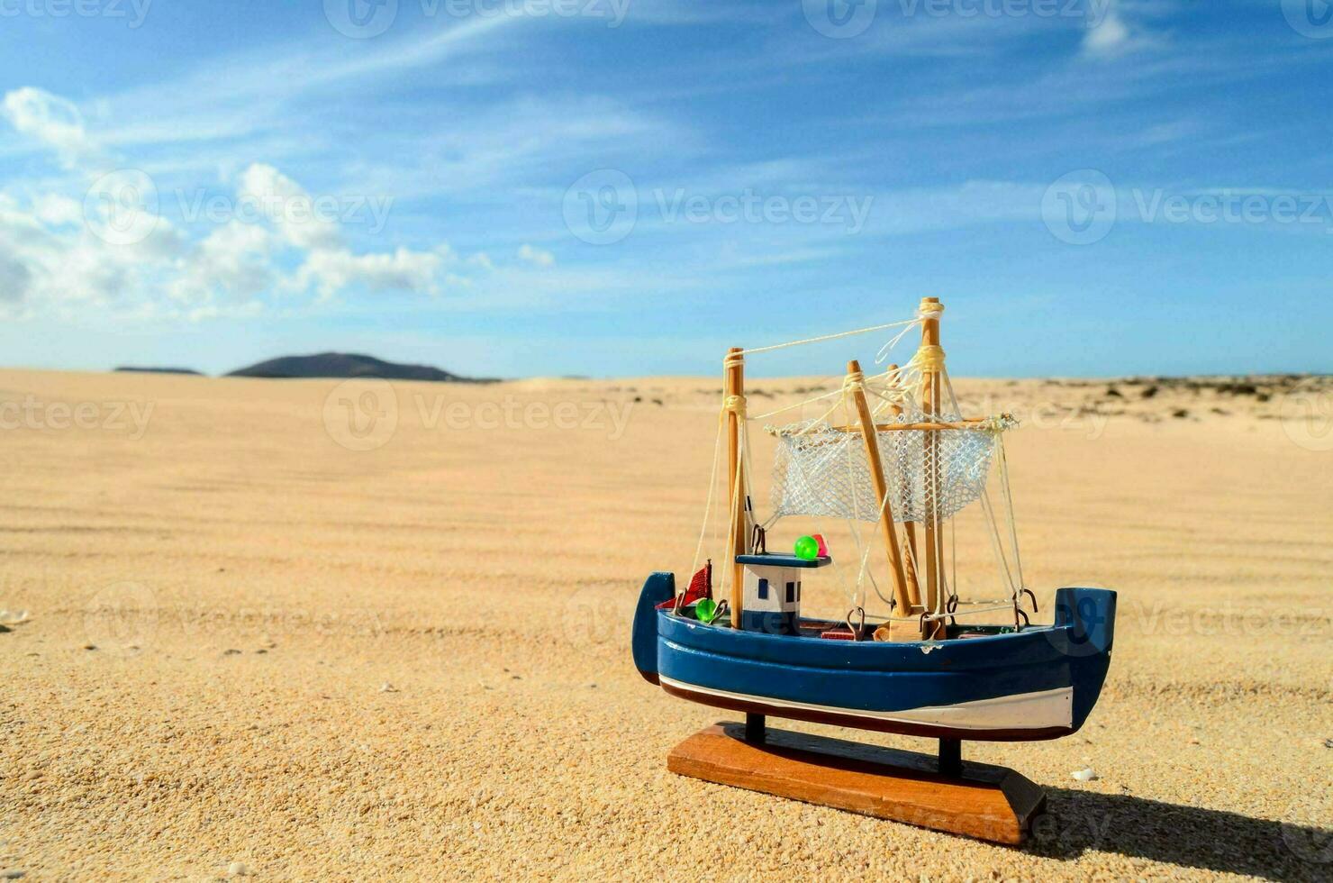 a toy boat sits on the sand photo