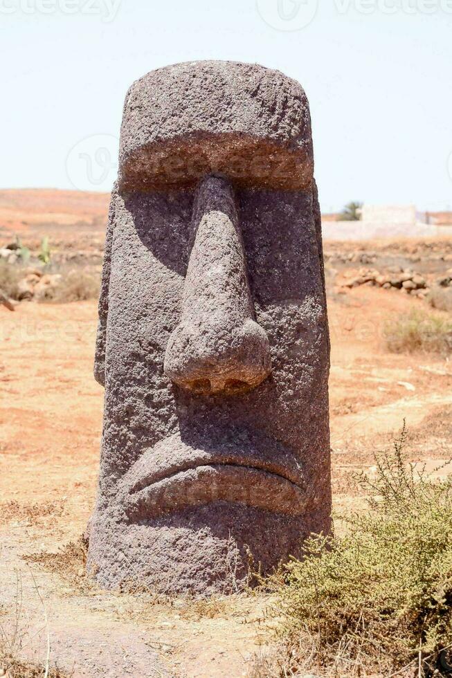 a large stone moai statue in the middle of a desert photo