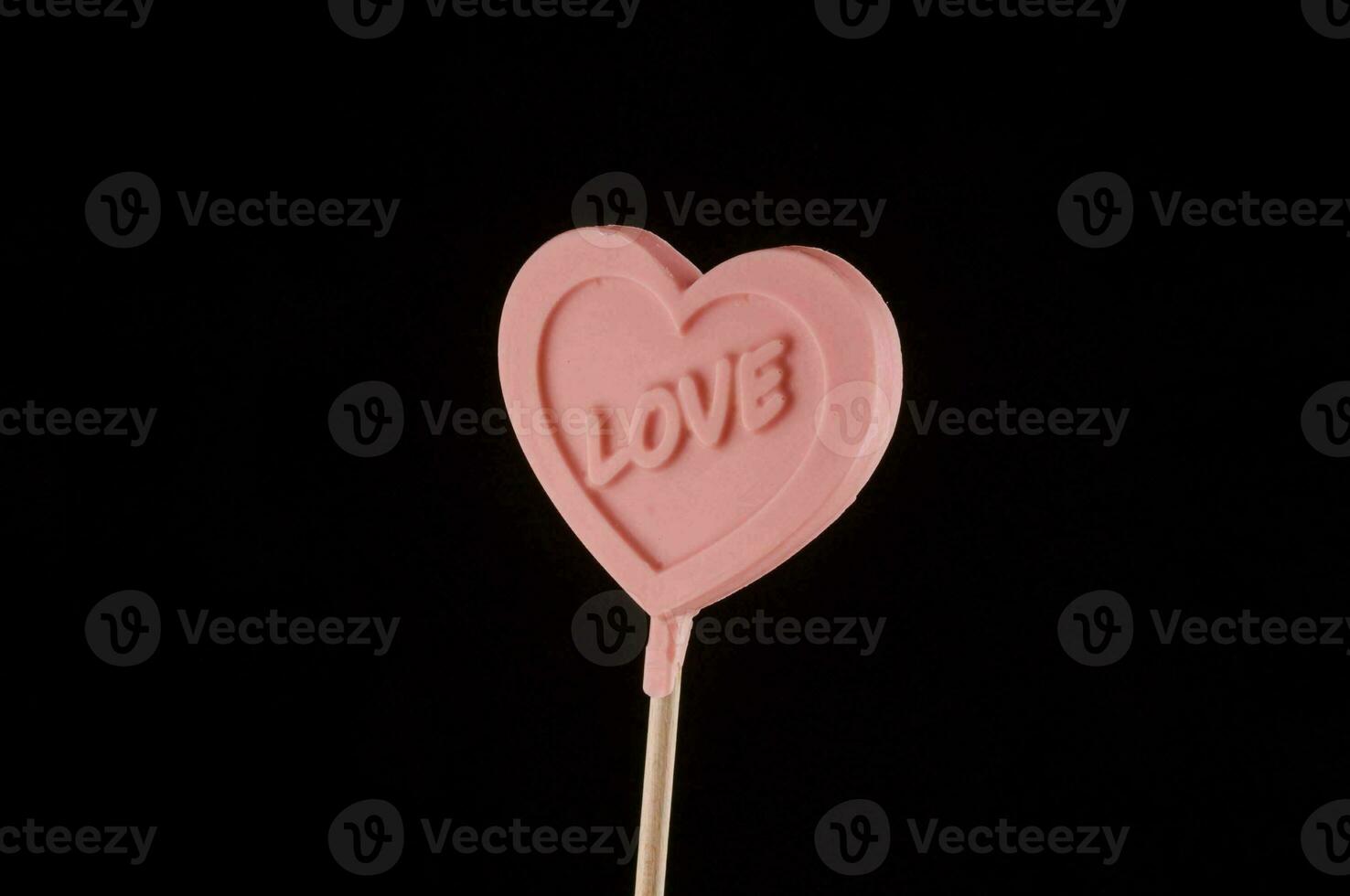 a pink heart shaped lollipop with the word love written on it photo