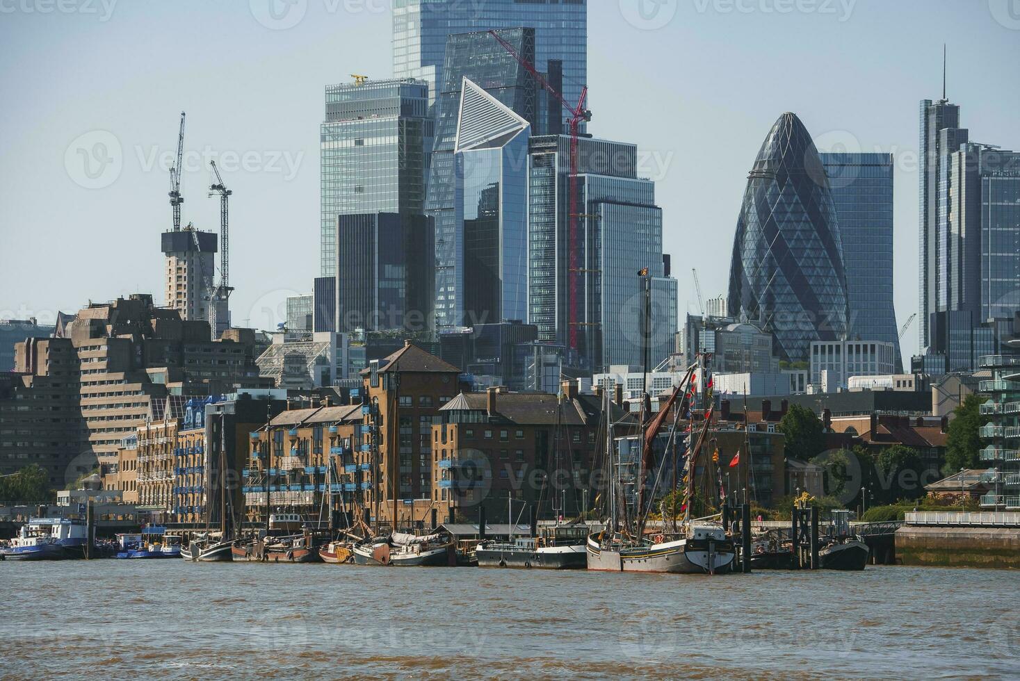 Boats moored at Thames riverbank with modern skyscrapers in background photo