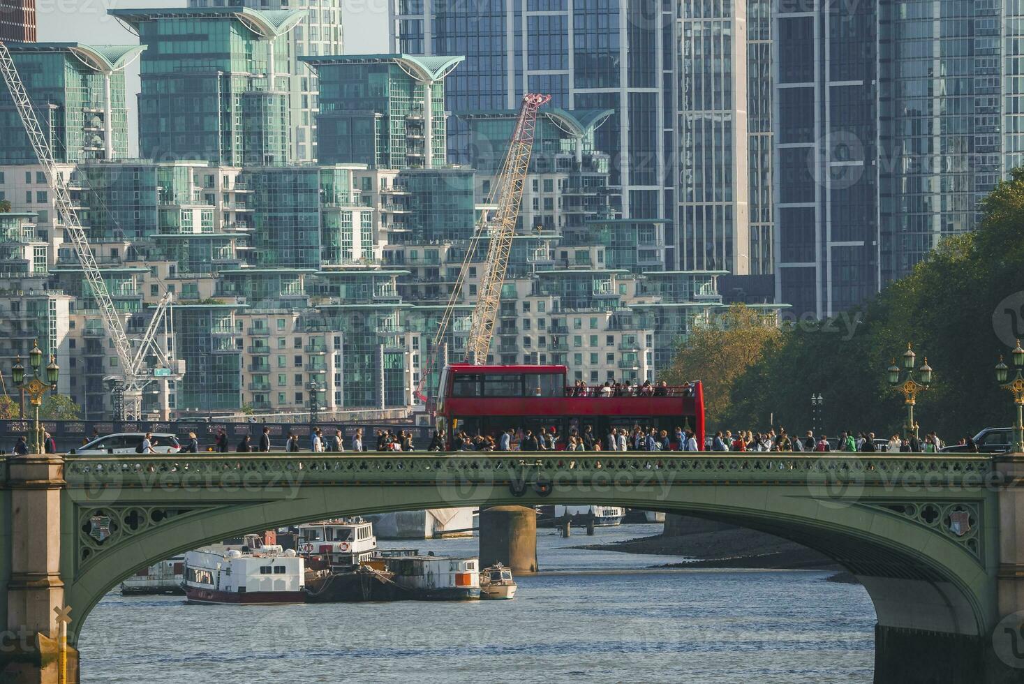 Crowd walking by tour bus on Westminster bridge with building in background photo