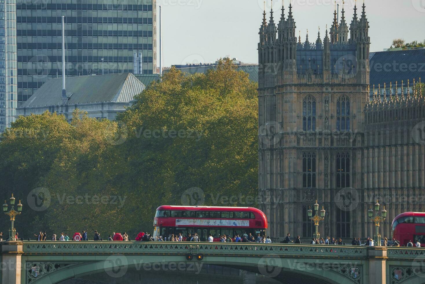 Crowd walking by tour bus on famous Westminster bridge towards palace in city photo