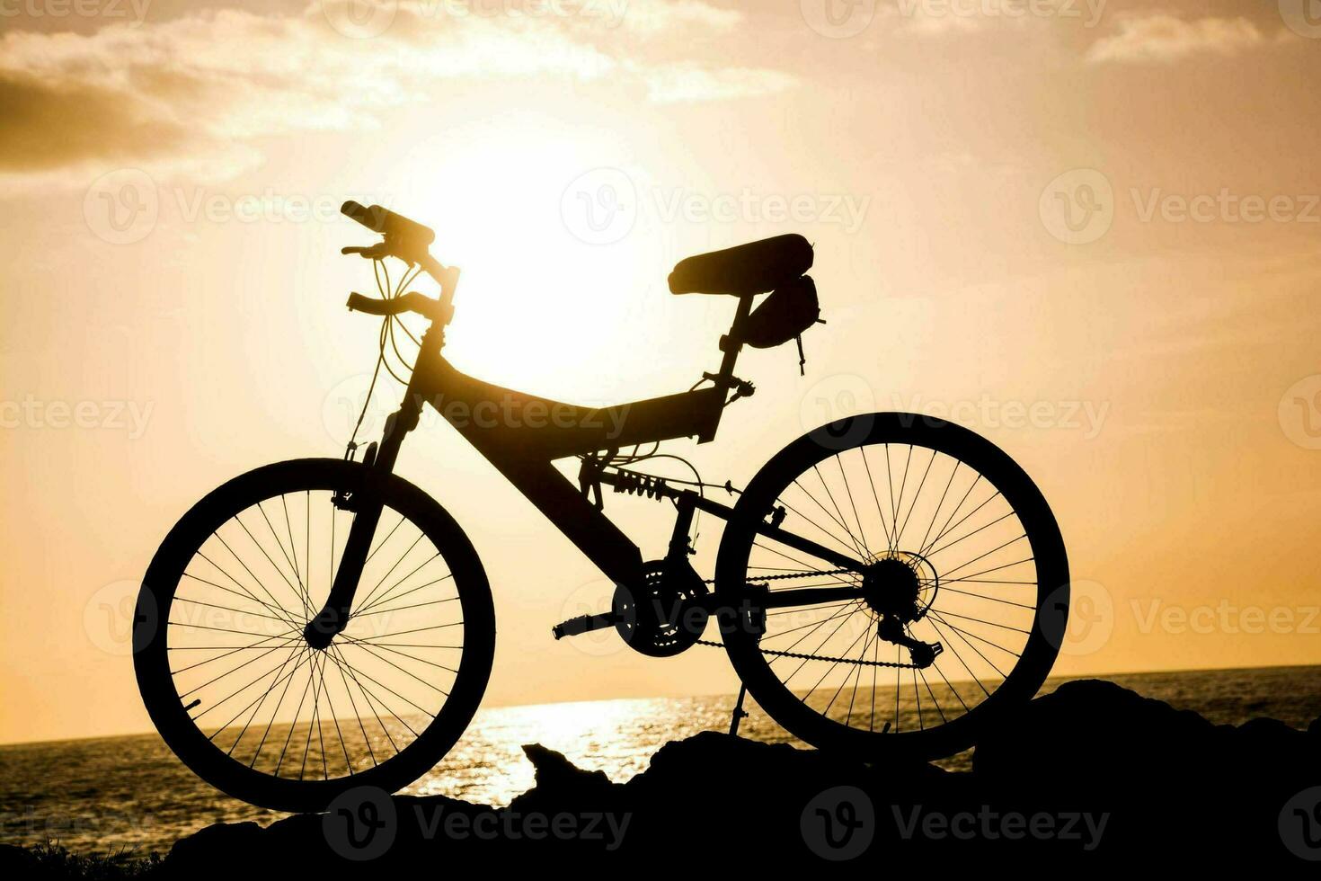 a bicycle is silhouetted against the sun at sunset photo