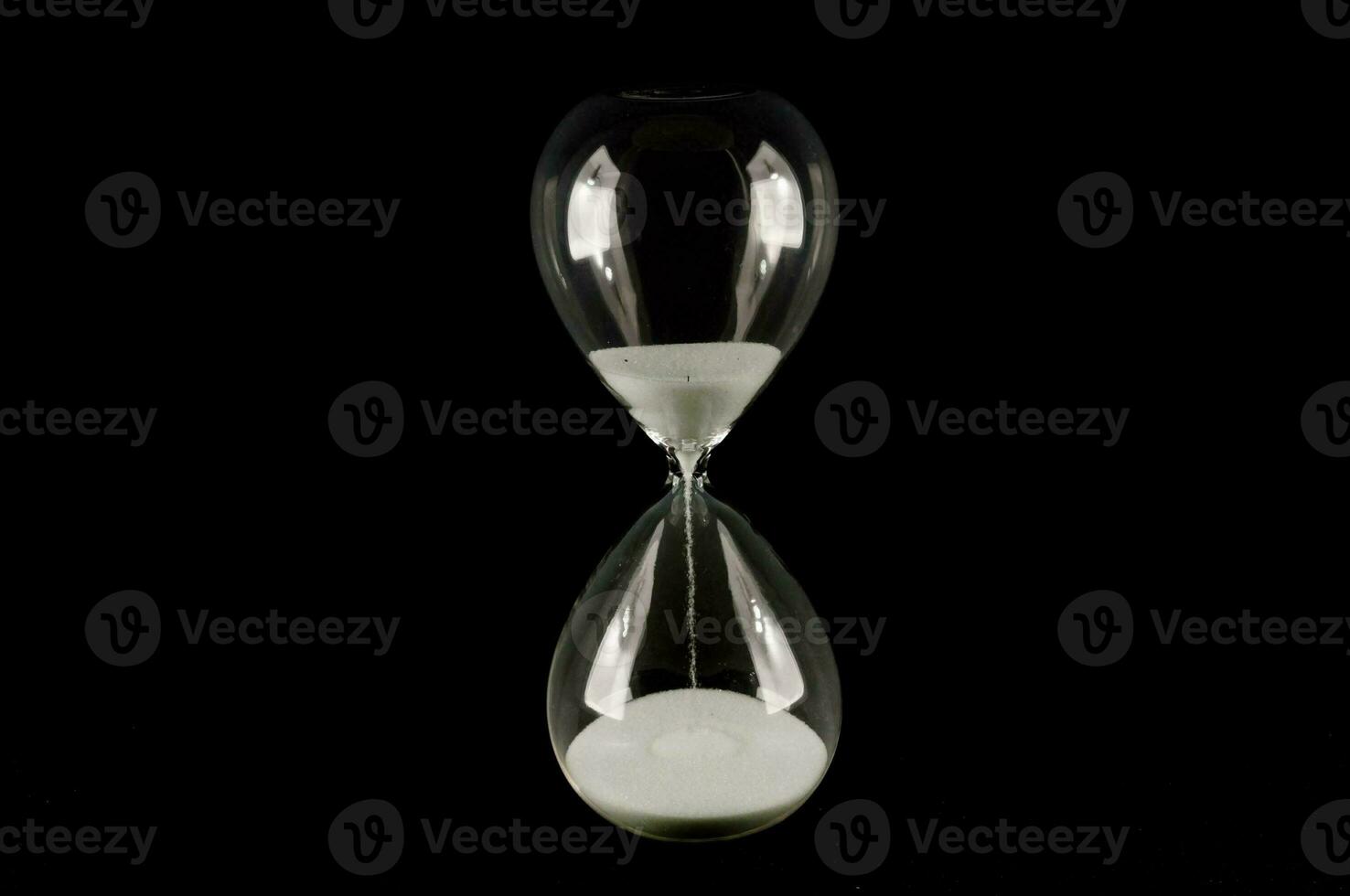 an hourglass with sand on a black background photo