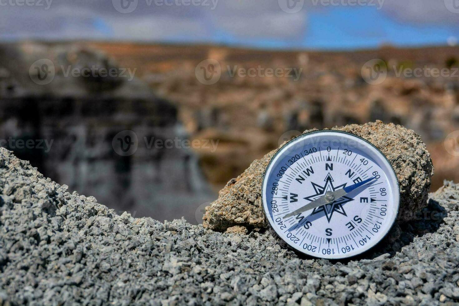 a compass on a rock in the middle of a desert photo