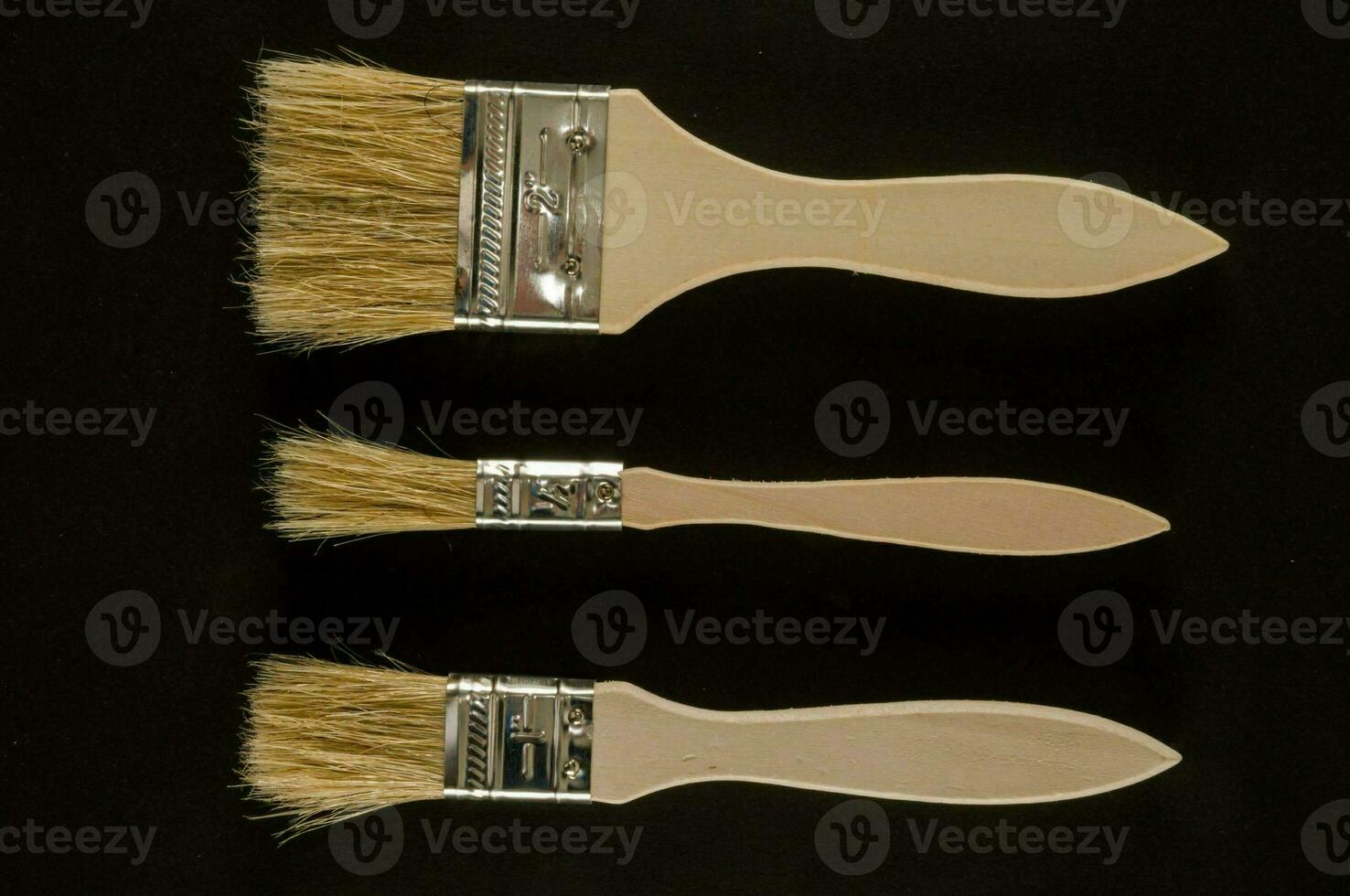 three brushes with wooden handles and bristles photo