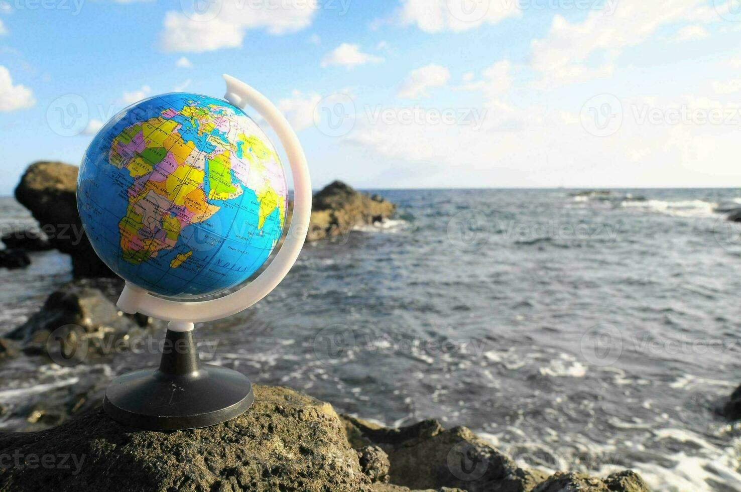 a globe on a rock in the ocean photo