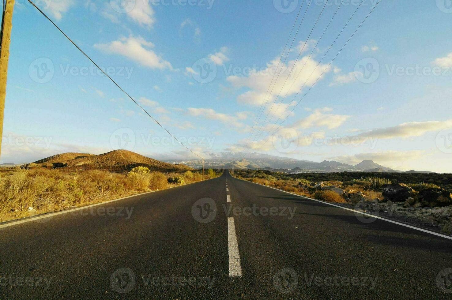 an empty road with a blue sky and mountains in the background photo