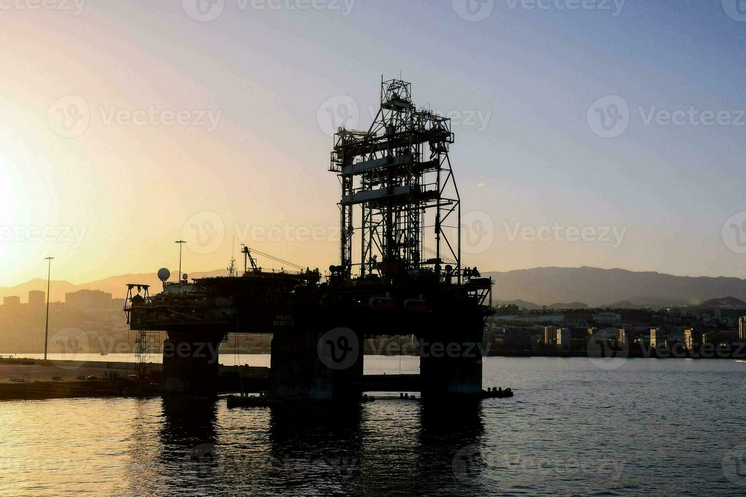 an oil rig in the water at sunset photo