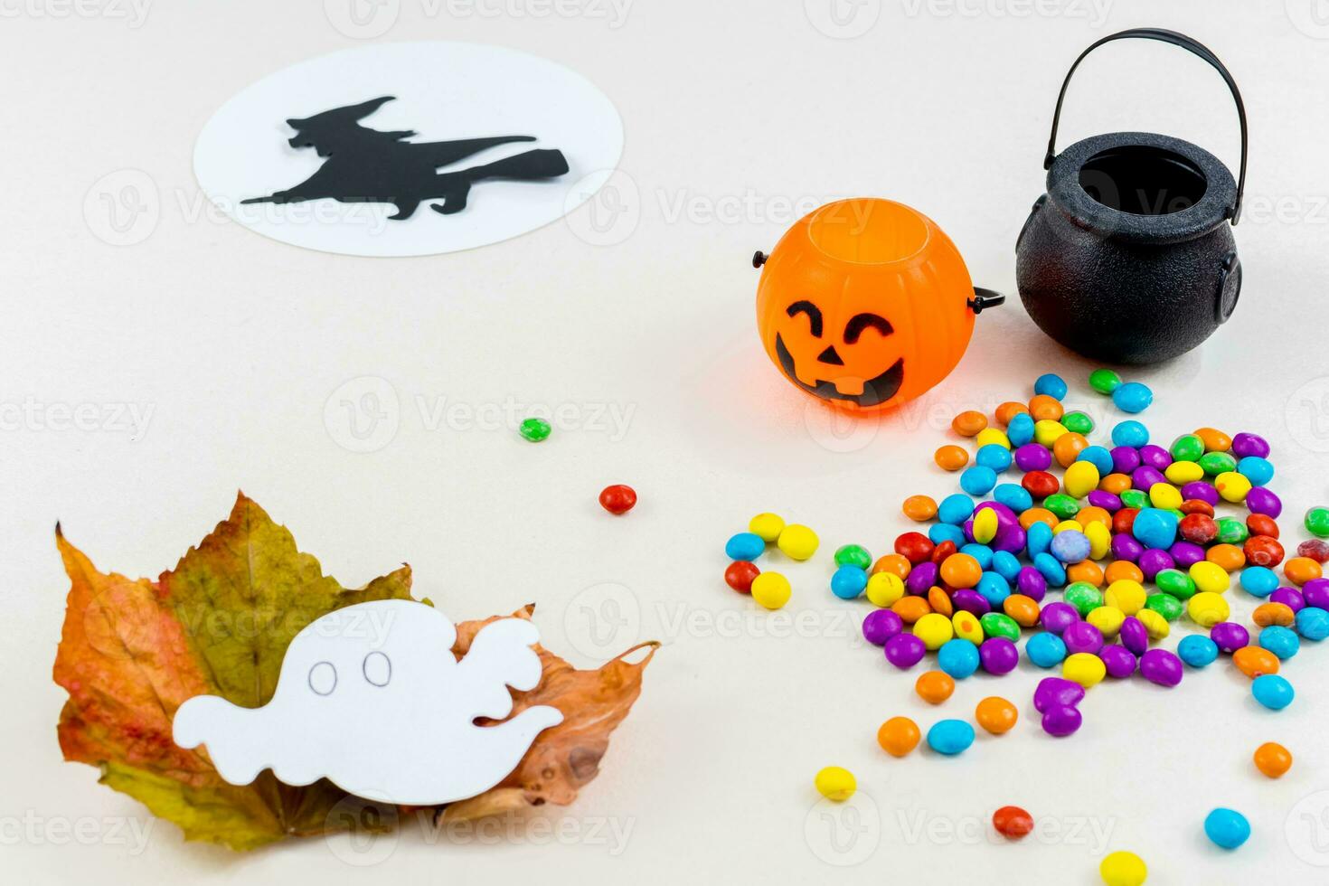 Halloween, pumpkins, witch silhouette flying on broomstick, full moon, colored sprinkles, cauldron, ghost, on white background. Selective focus. photo